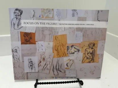 focus on the figure book resting on a bookstand with a collage of life drawings on the cover