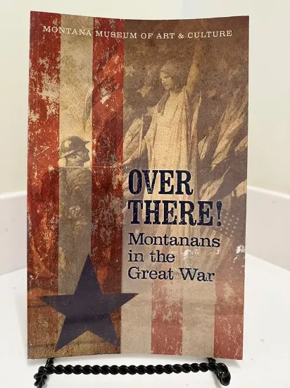 over there book resting on a bookstand with patriotic colors over a painting of the statue of liberty knighting a kneeling soldier