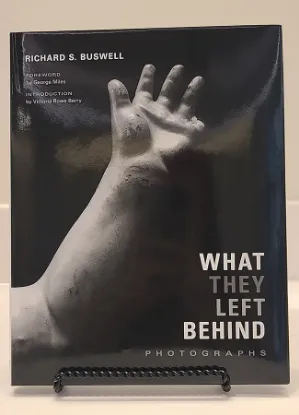 what they left behind book resting on a bookstand with a black and white picture of a damaged doll's arm on the cover