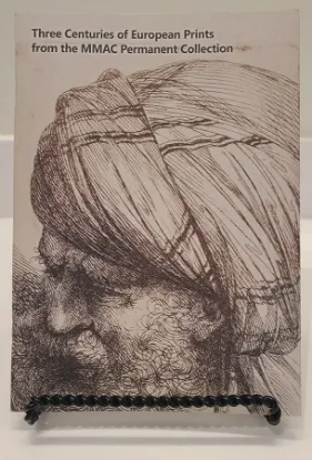 three centuries of european prints book resting on a bookstand with a line drawing of a man wearing a turban on the cover