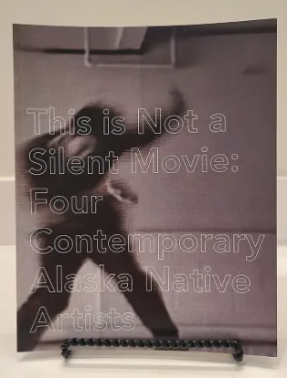 This is not a silent movie book resting on a bookstand with the cover featuring a silhouette of a person with their arm raised on a wall of tile